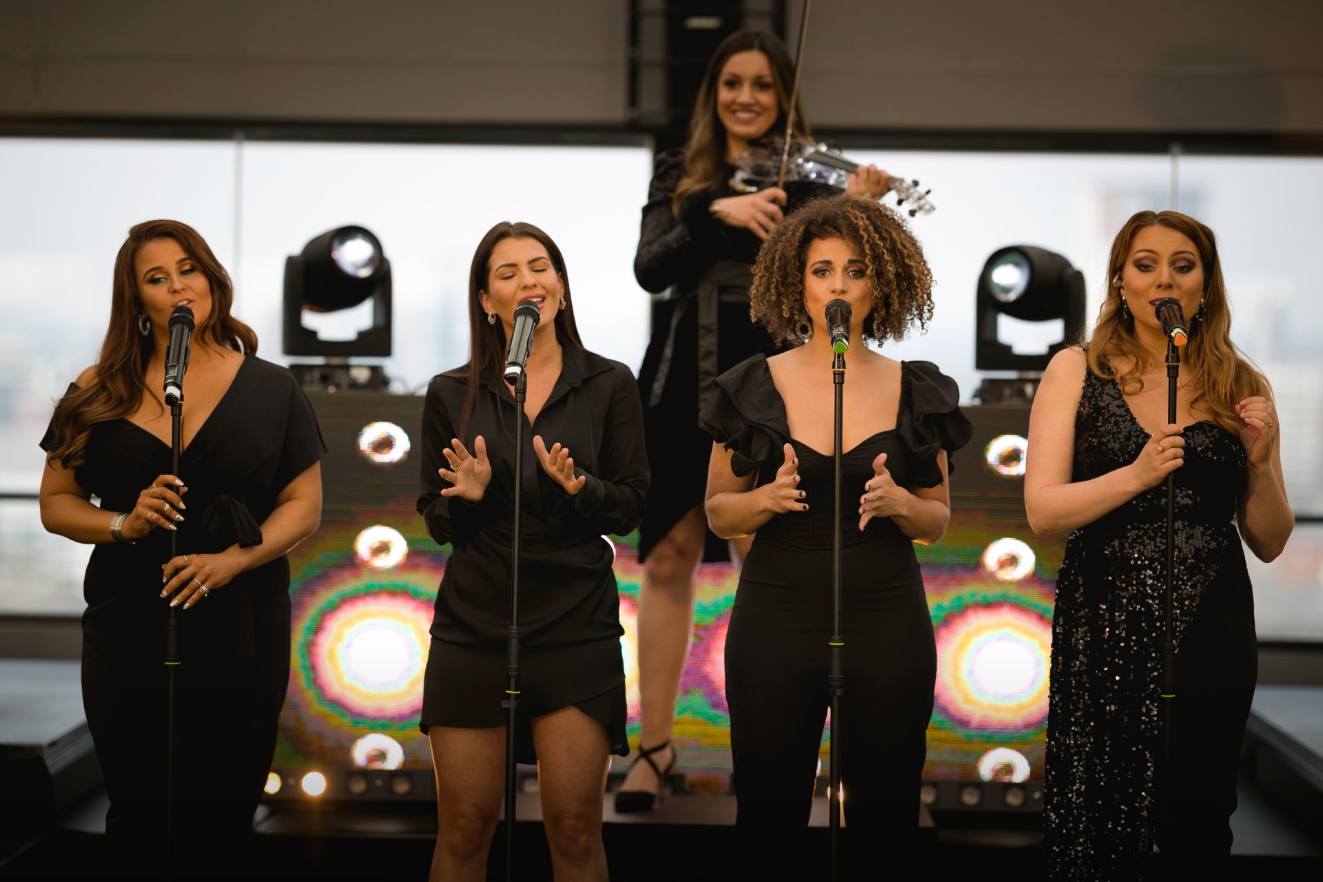 A group of women singing into microphones